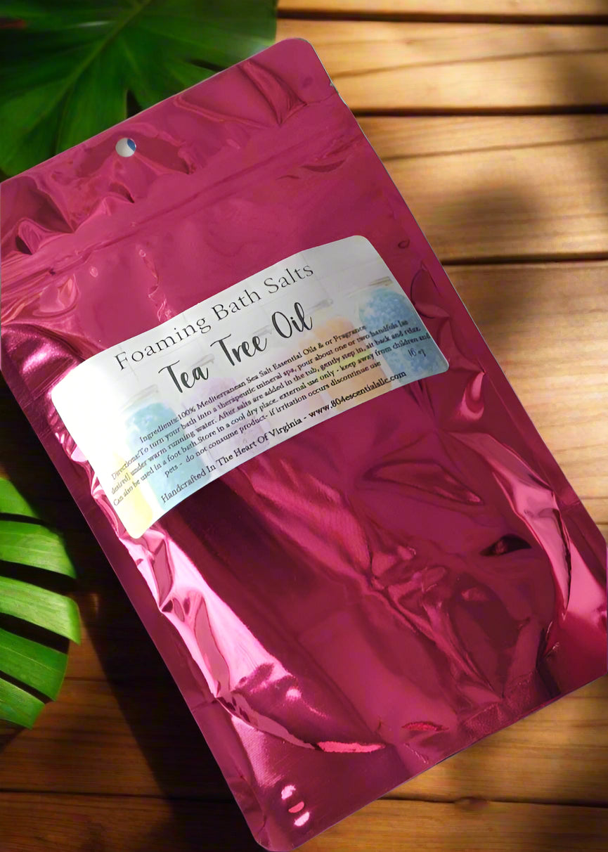 Pink packaging of Foaming Bath Salts with Tea Tree Oil on a wooden surface