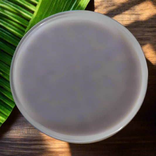 All-natural scoopable wax melts in a white bowl resting on a wooden surface and green leaf.