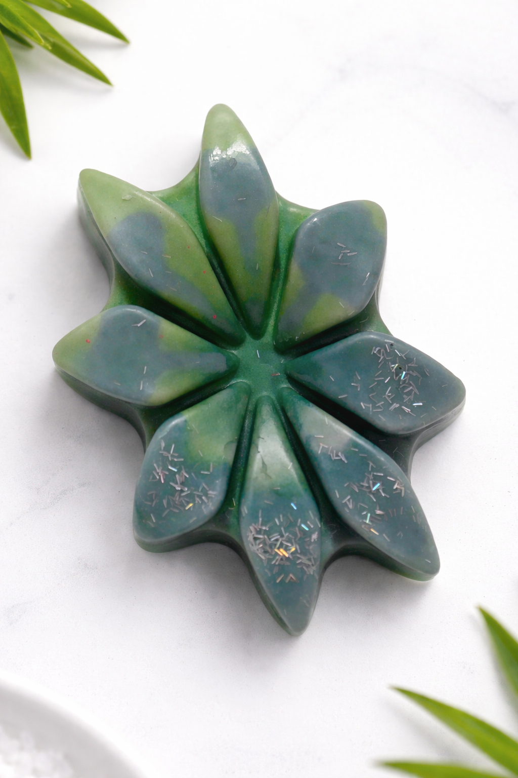 Green leaf-shaped wax melt bar on a white background with green leaves around