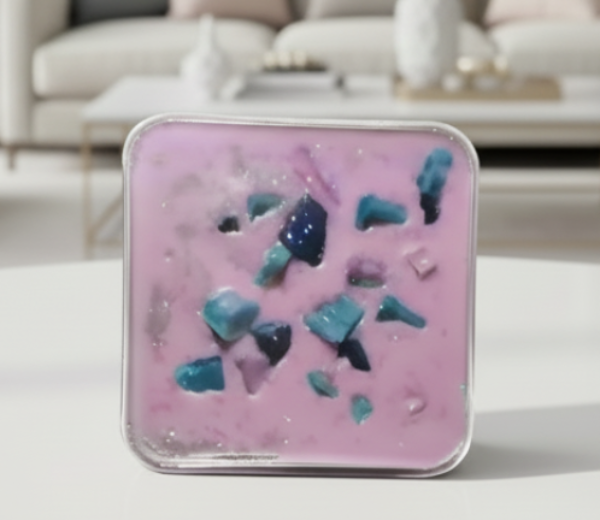 Pink and blue wax melt cake on a white surface with a blurred living room background