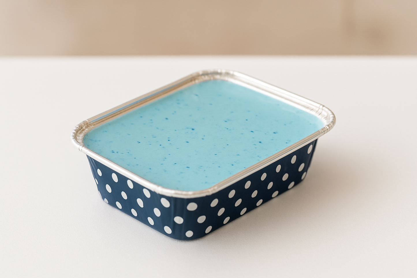 Blue polka dot container with blue wax melt on a white background
