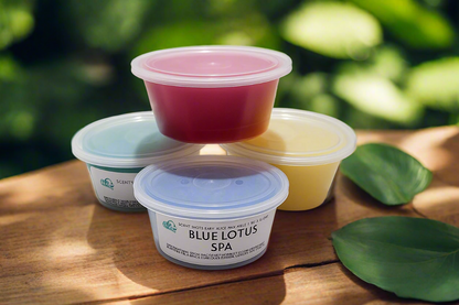 Four containers of Blue Lotus Spa product on a wooden surface with green leaves in the background